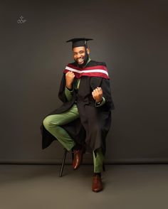 a man in a graduation gown sitting on a chair