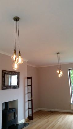 an empty living room with wood flooring and three light fixtures hanging from the ceiling