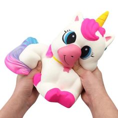 a hand holding a pink and white toy with a unicorn on it's back