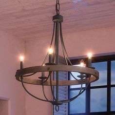 a chandelier hanging from the ceiling with three candles lit up in front of an open window