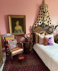 a bed sitting in a bedroom next to a painting on the wall and a chair