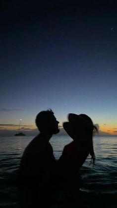 a man and woman kissing in the water at sunset