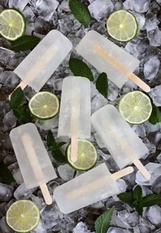 popsicles with limes and mint on top of ice cubes in a pile