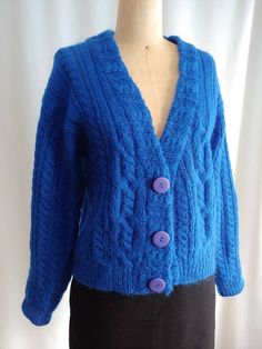 a woman's blue cardigan sweater with buttons on the front and back, sitting on a mannequin