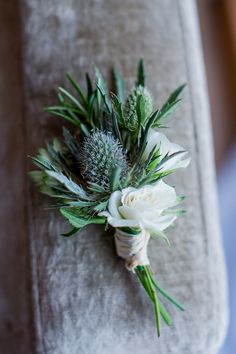 a boutonniere with white flowers and greenery on the back of a chair