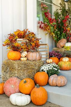 pumpkins and gourds are arranged on the front steps for fall decorating