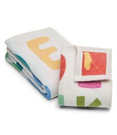 three folded towels on top of each other in different colors and shapes, with the word abc printed on them