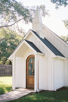 a small white church with a wooden door and steeple on the front entrance to it