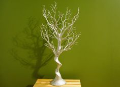 a small white tree sitting on top of a wooden table next to a green wall