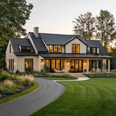 a large white house with lots of windows and grass in front of the house is lit up at night