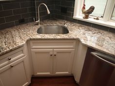 a kitchen with marble counter tops and stainless steel dishwasher in the corner sink