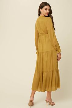 -Color: Green Mustard -Crinkle textured -Long sleeves with ruffle cuffs-Tiered skirt-Tie neck with self strap-Side seam pockets-Lined -Content: 100% Rayon -Hand wash/ Line dry -Imported -Runs true to size-Model is 5' 9" 31-24-35 and wearing a size Small Daywear Maxi Dress With Ruffles In Viscose, Daywear Viscose Maxi Dress With Ruffles, Viscose Maxi Dress With Ruffles For Daywear, Modest Long Sleeve Midi Dress With Ruffle Hem, Billowy Long Sleeve Midi Dress With Ruffle Hem, Flowy Ruffled Midi Dress For Work, Fall Midi Dress With Billowy Ruffle Hem, Modest Ruffled Maxi Dress For Fall, Modest Ruffle Maxi Dress For Fall