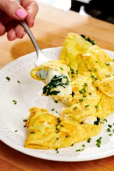 a person eating an omelet on a white plate with a fork in it