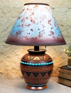 a lamp sitting on top of a table next to a potted plant and books