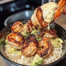 someone is dipping some shrimp over rice in a bowl