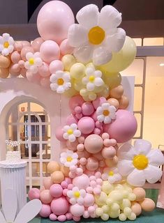 there is a cake made out of balloons and flowers on the table in front of it