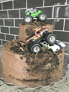 a chocolate cake with monster trucks on top