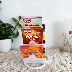 three packets of candies stacked on top of each other next to a potted plant