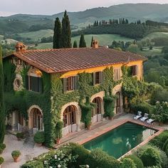 an outdoor pool surrounded by greenery next to a large house with a swimming pool