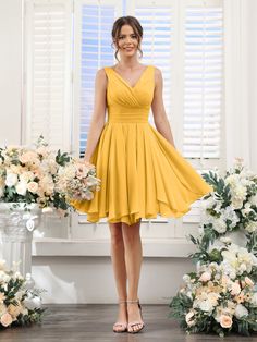 a woman standing in front of flowers wearing a yellow bridesmaid dress and heels