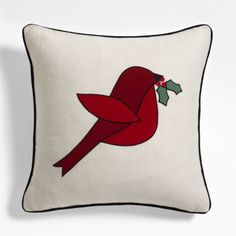 a red bird with holly on it's back is sitting on a white pillow