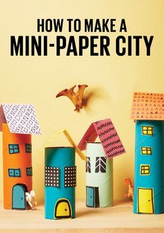 several paper houses are lined up on a table next to a bird flying over them