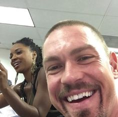 a man taking a selfie with two other people in the background smiling at the camera