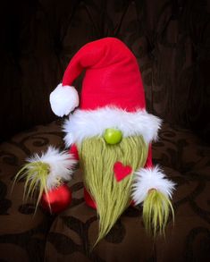 a green and white santa hat sitting on top of a couch next to a red ornament