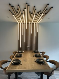 a wooden table with black plates on it in front of a wall sculpture made from wood sticks