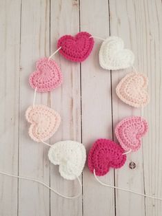 crocheted hearts hanging on a string with white and pink yarn in the middle