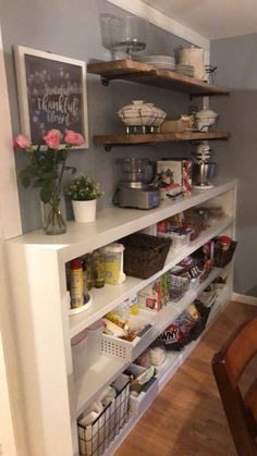 an open pantry with lots of food and drinks on the shelves, next to a dining room table