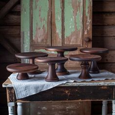 four wooden pedestals sitting on top of a table in front of an old door