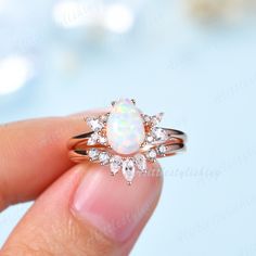 a woman's hand holding a ring with an opal and diamonds on it