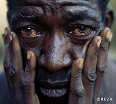 a close up of a person with his hands on their face and eyes covered in mud