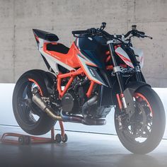 an orange and black motorcycle parked next to a wall