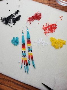 beaded earrings are laid out on a piece of paper next to scissors and beads