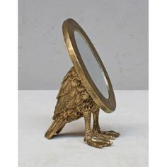 a gold bird figurine with a mirror on it's head