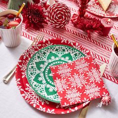 a red and green plate with white snowflakes on it next to silverware