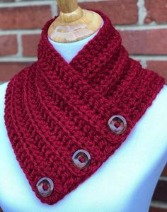 a close up of a mannequin wearing a red knitted cowl with buttons