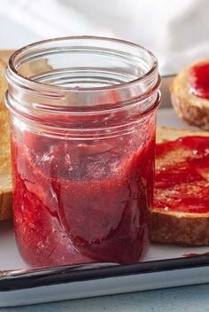 there is a jar of jam next to toast on the plate and another piece of bread