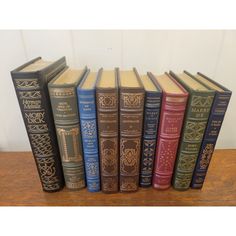 a row of old books sitting on top of a wooden table next to each other