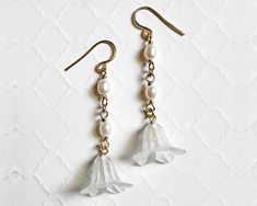 Elevate your style with these exquisite wire-wrapped white flower pearl drop earrings. Handcrafted with non-tarnish gold wire, delicate white acrylic flowers, and lustrous oval white pearl beads, each pair is a unique work of art. The hammered ear wires, nickel-free and lead-free, ensure both style and comfort. These earrings measure 2.3 inches long and come packaged in a charming organza bag. Sold by the pair, they're the perfect accessory for any occasion. Measurement & Specs DIMENSION: 2.3 Inch Long  COLOR: White PLATING: Gold Delicate White Teardrop Flower Earrings, White Teardrop Flower Earrings With Pearl Drop, Delicate White Wire Wrapped Pearl Earrings, Feminine White Flower Earrings With Pearl Drop, Delicate White Pearl Earrings With Ear Wire, Spring White Pearl Earrings, Delicate White Pearl Flower Earrings, Delicate White Flower Earrings With Ear Wire, White Dangle Pearl Earrings With French Hook