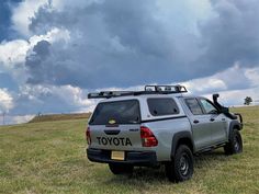 a toyota truck parked in a grassy field under a cloudy sky with the word toyota written on it