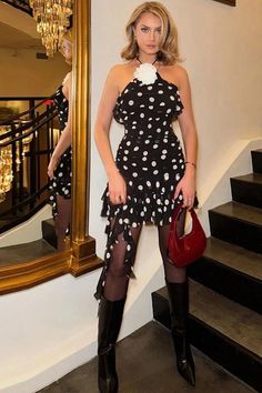 a woman standing in front of a mirror holding a red purse and posing for the camera