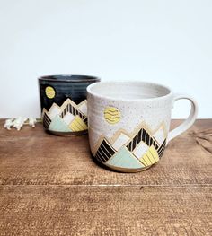 two coffee mugs sitting on top of a wooden table