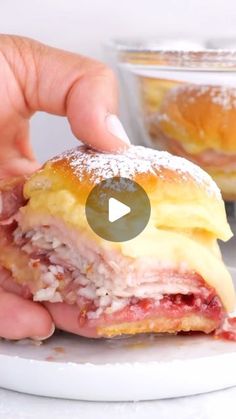 a person is holding a ham and cheese sandwich on a plate with powdered sugar