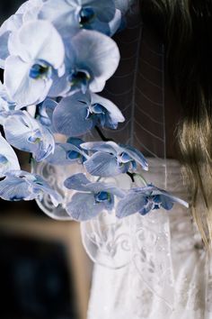 a close up of a woman holding flowers in her hands and wearing a white dress