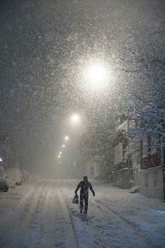 a man walking down a snow covered street at night