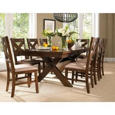 a dining room table and chairs with flowers in vases on the top one side