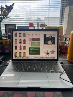 an open laptop computer sitting on top of a desk next to a vase with flowers